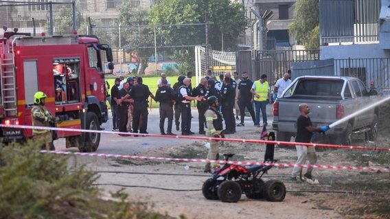 Israelische Polizisten und Feuerwehrleute arbeiten am Ort eines Raketenangriffs auf den israelisch kontrollierten Golanhöhen. © AP/dpa Foto: Gil Eliyahu