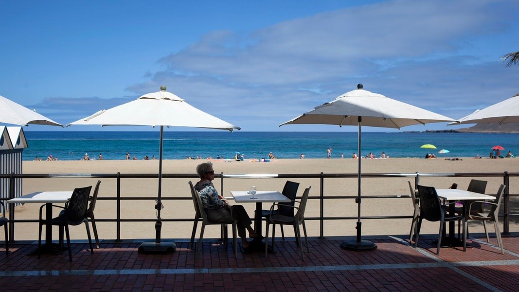 Eine Frau sitzt auf der Terrasse einer Bar am Strand in Las Palmas de Gran Canaria.