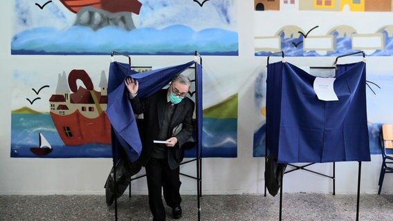 Ein Mann verlässt eine Wahlkabine in Athen © Thanassis Stavrakis/AP/dpa 