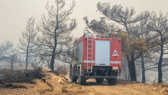 Ein Löschfahrzeug bahnt sich seinen Weg durch abgebrannte Bäume während eines Waldbrandes auf der griechischen Insel Rhodos. © Lefteris Damianidis/InTime News/AP/dpa 