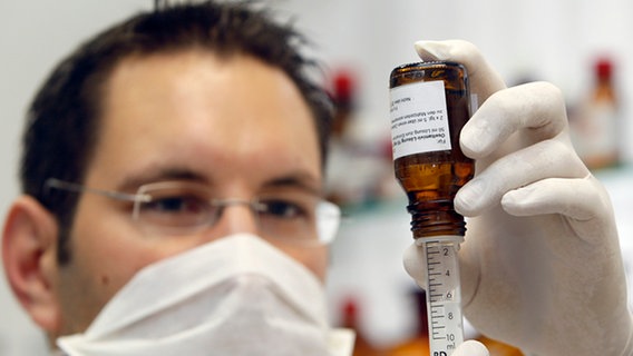 Ein Apotheker füllt eine Spritze mit einem Grippemedikament. © AP / Frank Augstein 