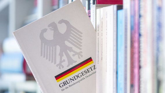 Ein Grundgesetz steckt in einem Bücherregal. © dpa Foto: Hendrik Schmidt