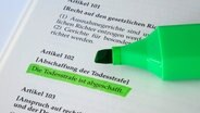 Ein grüner Filzstift liegt auf einer aufgeschlagenen Ausgabe des Grundgesetzes, auf der im Artikel 102 zur Abschaffung der Todesstrafe. © picture alliance / Sascha Steinach/dpa-Zentralbild/dpa | Sascha Steinach 