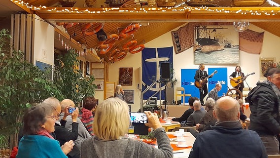 Festlich geschmückter Saal mit Publikum in der Seemannsmission. © NDR Foto: Aniela von Porthan