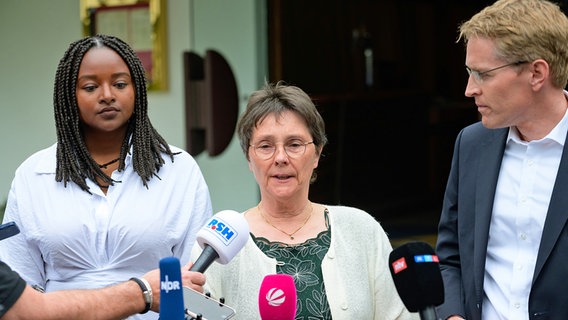 Daniel Günther, Ministerpräsident von Schleswig-Holstein (CDU), steht neben Monika Heinold (M.) und Aminata Touré von den Grünen bei einem Interview. © dpa picture alliance Foto: Jonas Walzberg