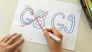 Eine Schülerin einer Schule hat "G8" auf einem Blatt Papier durchgestrichen, "G9" daneben bleibt unberührt. (Foto vom 24.06.2022) © picture alliance/dpa | Friso Gentsch 