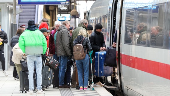 Pasażerowie tłoczą się przed drzwiami głównego dworca kolejowego w Hamburgu, wchodząc do pociągu Deutsche Bahn ICE.