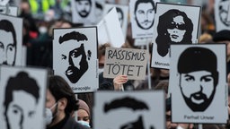 Mit Plakaten und Bildern der Ermordeten erinnern am 19.2.2022 Teilnehmer einer Gedenkveranstaltung auf dem Hanauer Marktplatz an die Opfer © Boris Roessler/dpa 