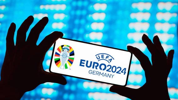 Ein Mann hält ein Smartphone in der Hand, auf dem das Logo der UEFA European Football Championship zu sehen ist © picture alliance / Sipa USA Foto: SOPA Images