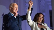 US-Präsident Joe Biden hebt die Hand von US-Vizepräsidentin Kamala Harris, nachdem er vom Balkon des Weißen Hauses aus das Feuerwerk zum Unabhängigkeitstag über der National Mall betrachtet hat, Donnerstag, 4. Juli 2024, in Washington. © Evan Vucci/AP/dpa 