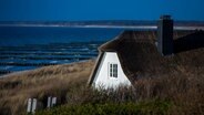 Ein Haus mit Reetdach am Strand von Ahrenshoop (Mecklenburg-Vorpommern) in den Dünen am Strand. © picture alliance / ZB Foto: Jens Büttner