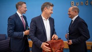 Bundeskanzler Olaf Scholz, Robert Habeck und Christian Lindner nehmen an einer Pressekonferenz zum Haushaltsplan 2025 teil. © dpa-Bildfunk Foto: Michael Kappeler