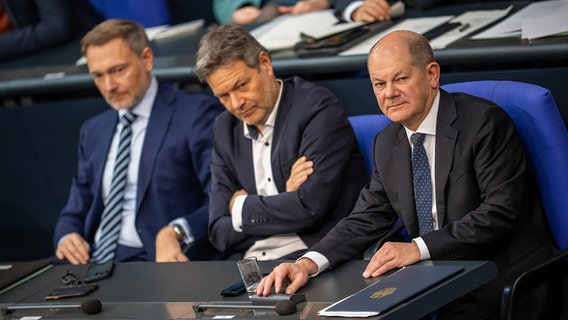 Bundeskanzler Olaf Scholz (SPD, r), verfolgt neben Robert Habeck (Bündnis 90/Die Grünen, M), Bundesminister für Wirtschaft und Klimaschutz, und Christian Lindner (FDP), Bundesminister der Finanzen, die Debatte nach einer Regierungserklärung zur Haushaltslage im Bundestag. © picture alliance Foto: Michael Kappeler