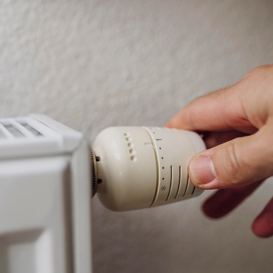 Ein Mann dreht am Thermostat einer Heizung © picture alliance Foto: Westend61 | HalfPoint