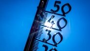 Die Sonne ist hinter einem Thermometer zu sehen. © Jens Büttner/dpa Foto: Jens Büttner