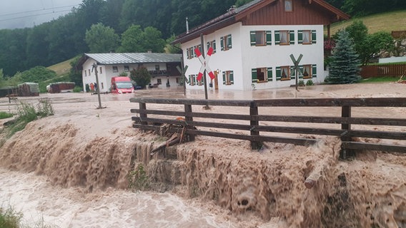 Wasser fließt über einen Platz vor einem Haus in der bayerischen Gemeinde Bischofswiesen im Landkreis Berchtesgadener Land. © dpa Foto: Kilian Pfeiffer