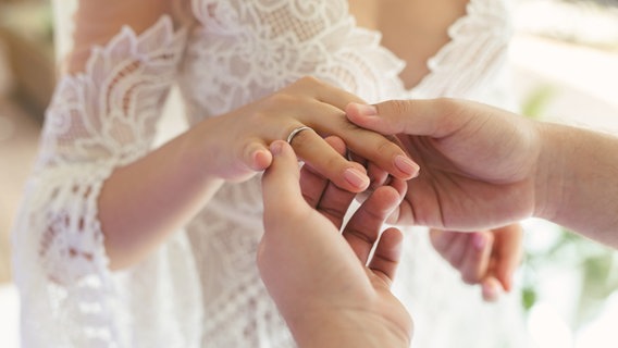 Ein Bräutigam steckt seiner Braut den Ehering an den Ringfinger. © Colourbox Foto: Artem Zakharov