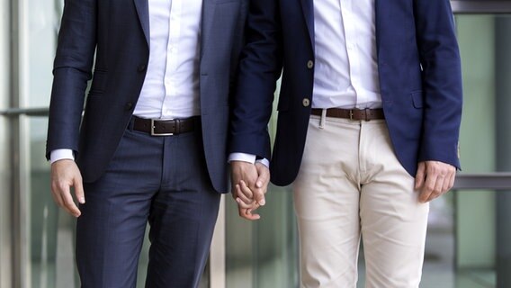 Zwei Männer im Anzug gehen Hand in Hand. © fotolia Foto: wernerimages