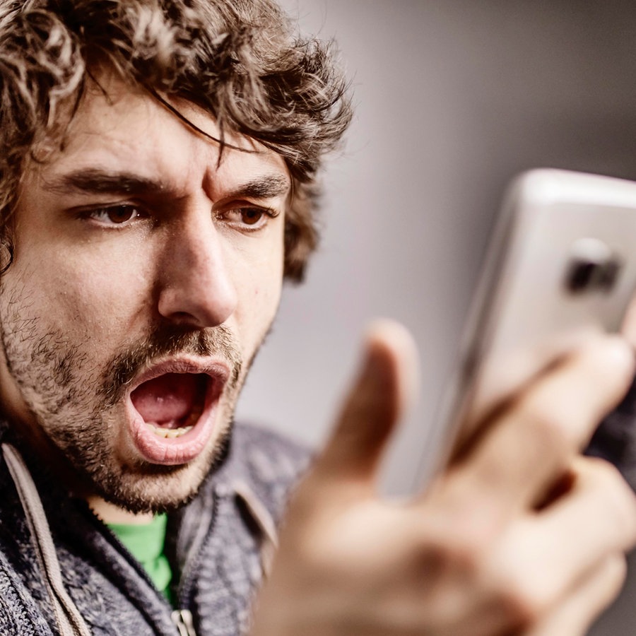 Junger Mann schaut verärgert auf sein Smartphone © picture alliance / imageBROKER Foto: Jan Tepass