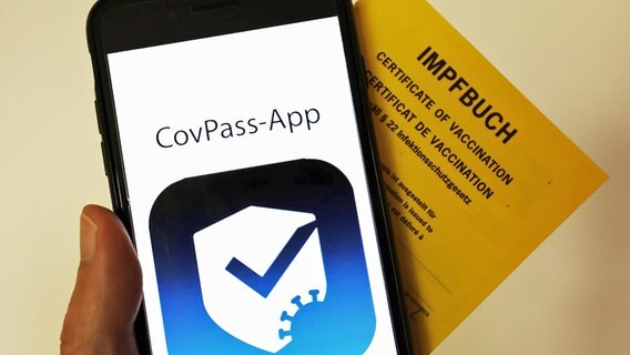 Das Logo der CovPass-App ist neben einem Impfbuch auf einem Smartphone zu sehen. © dpa-Zentralbild-Pool/dpa Foto: Oliver Berg