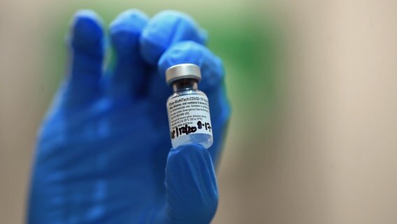 Eine Hand mit blauem Handschuh hält eine Ampulle mit dem Pfizer/Biontech Corona-Impfstoff. © dpa-Bildfunk Foto: Victoria Jones/PA Wire/dpa