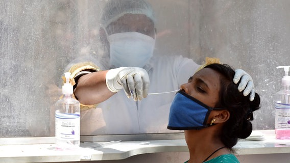 Ein Mitarbeiter des Gesundheitswesens nimmt in Indien von einer Frau einen Abstrich für einen Coronatest. © Str./Xinhua/dpa 