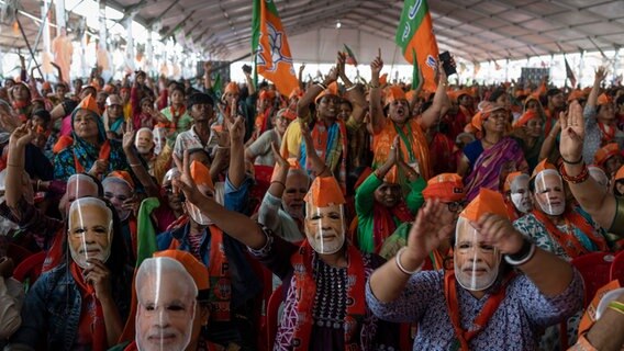 Anhänger der Bharatiya Janata Party (BJP) tragen Masken des indischen Premierministers Narendra Modi während einer Wahlkampfveranstaltung rund zwei Wochen vor Beginn der Parlamentswahl in Indien. © Altaf Qadri/AP/dpa 