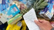 Ein Supermarkt-Kunde überprüft seinen Kassenbon von einem gut gefüllten Einkaufswagen © picture alliance / SvenSimon Foto: Frank Hoermann/SVEN SIMON