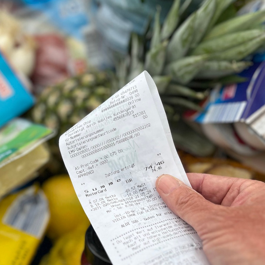 Ein Supermarkt-Kunde überprüft seinen Kassenbon von einem gut gefüllten Einkaufswagen © picture alliance / SvenSimon Foto: Frank Hoermann/SVEN SIMON