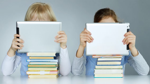 Zwei Schülerinnen mit einem Tabletcomputer vor dem Gesicht. © fotolia Foto: Uwe Annas