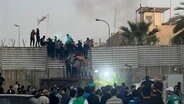 Demonstranten erklimmen eine Mauer an der schwedischen Botschaft in Bagdad. © Ali Jabar/AP 