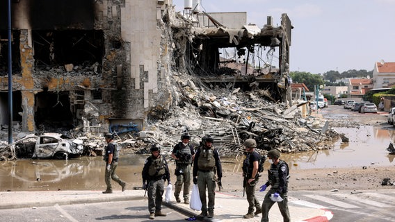 Israelische Sicherheitskräfte versammeln sich nach Angriffen militanter Palästinenser vor einem zerstörten Gebäude in der Grenzstadt Sderot. © REUTERS/Ronen Zvulun 
