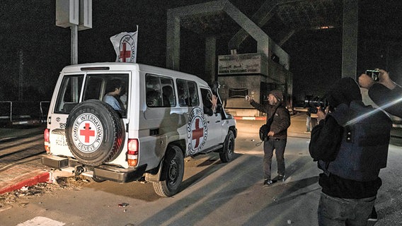 Ein Fahrzeug des Roten Kreuzes fährt im Dunklen im Gazastreifen auf einer Straße Richtung Grenzübergang nach Ägypten. © dpa-Bildfunk/AP Foto: Fatima Shbair