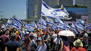 Demonstranten schwenken auf einer Straße in Tel Aviv israelische Flaggen. © dpa-Bildfunk/AP Foto: Leo Correa