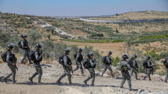 Israelische Soldaten gehen durch ein zerstörtes Gebiet. © picture alliance / Middle East Images | Mosab Shawer Foto: Mosab Shawer