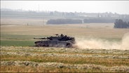 Ein israelischer Armeepanzer wirbelt Staub auf, als er im Süden Israels  nahe der  Grenze zum südlichen Gazastreifen durch das Gelände fährt. © icture alliance / newscom | Jim Hollander Foto: Jim Hollander