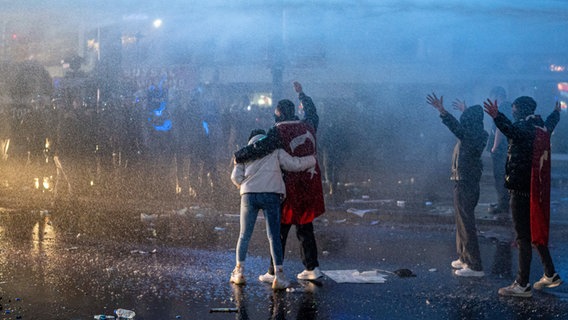 Ein Paar mit einer türkischen Flagge um den Hals wehrt sich während der Demonstration gemeinsam gegen den Einsatz von Wasserwerfern. © Tunahan Turhan/SOPA Images via ZUMA Press Wire/dpa Foto: Tunahan Turhan