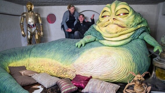 Kirstin und Marc Langrock stehen neben der Nachbildung der Kinofigur "Jabba" in einem der 29 nachgebildeten Set-Szenen aus unterschiedlichen Filmen der "Star Wars"-Serie.  
