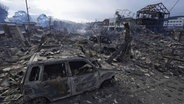 Ein verbranntes Auto steht zwischen Trümmern nach einem Feuer das nach einem starken Erdbeben in Wajima, Präfektur Ishikawa ausgebrochen war. © Kyodo News/AP/dpa 