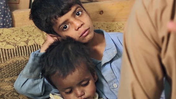 Ein Junge mit leerem Blick, daneben ein Kleinstkind. © ARD 