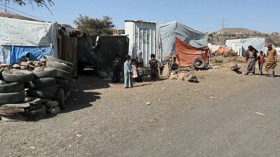 Flüchtlingslager mit einigen Menschen neben Zelten. © ARD 