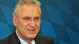 Joachim Herrmann steht in einem dunklen Anzug vor einer dunkelblauen Wand. Joachim Herrmann steht in einem dunklen Anzug vor einer dunkelblauen Wand. © Bayerisches Staatsministerium für Inneres, Pressestelle
