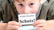 Kind mit einem Schild auf dem steht 'Kinder brauchen Schutz'. © Xenia1972 - Fotolia.com 