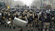 Bereitschaftspolizisten blockieren in der kasachischen Hauptsadt Almaty eine Straße, um Demonstranten aufzuhalten. Aus Protest gegen hohe Energiepreise sind in Kasachstan Tausende Menschen auf die Straße gegangen. © dpa-Bildfunk 