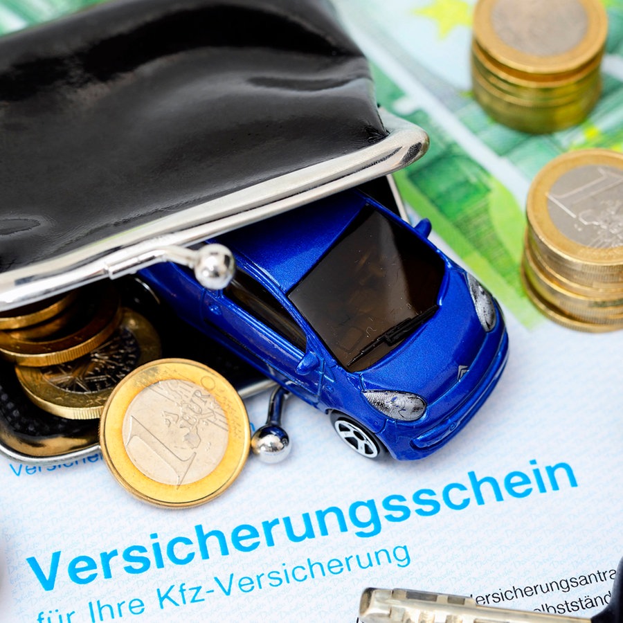 Ein Miniaturauto im Portemonnaie liegt auf einem KFZ-Versicherungsschein zusammen mit Euro-Geldmünzen und -scheinen © picture alliance Foto: Christian Ohde