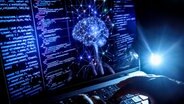 Eine Person arbeitet am Rechner, auf dessen Bildschirm ein durch Künstliche Intelligenz generiertes Illustrationsbild mit Zahlencodes zu sehen ist. © Oliver Berg/dpa Foto: Oliver Berg