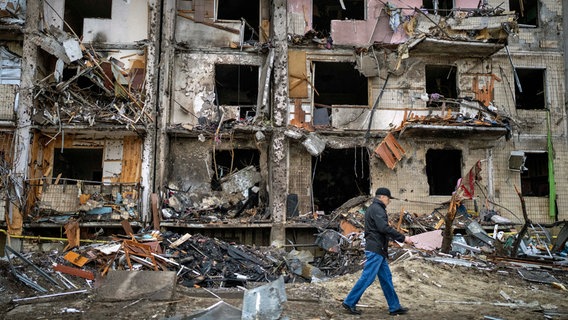 Ein Mann geht in Kiew an einem Gebäude vorbei, das nach einem Raketenangriff beschädigt wurde. © dpa-Bildfunk 