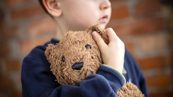 Ein trauriges Kind hält seinen Teddybär in der Hand © photothek Foto: Thomas Trutschel
