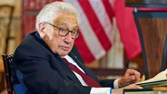 Der ehemalige US-amerikanische Außenminister Henry Kissinger sitzt an einem Tisch. © dpa picture alliance/ASSOCIATED PRESS Foto: Jacquelyn Martin
