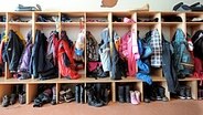 Jacken und Rucksäcke von Kindern hängen an einer Garderobe. © imago/Thomas Müller 